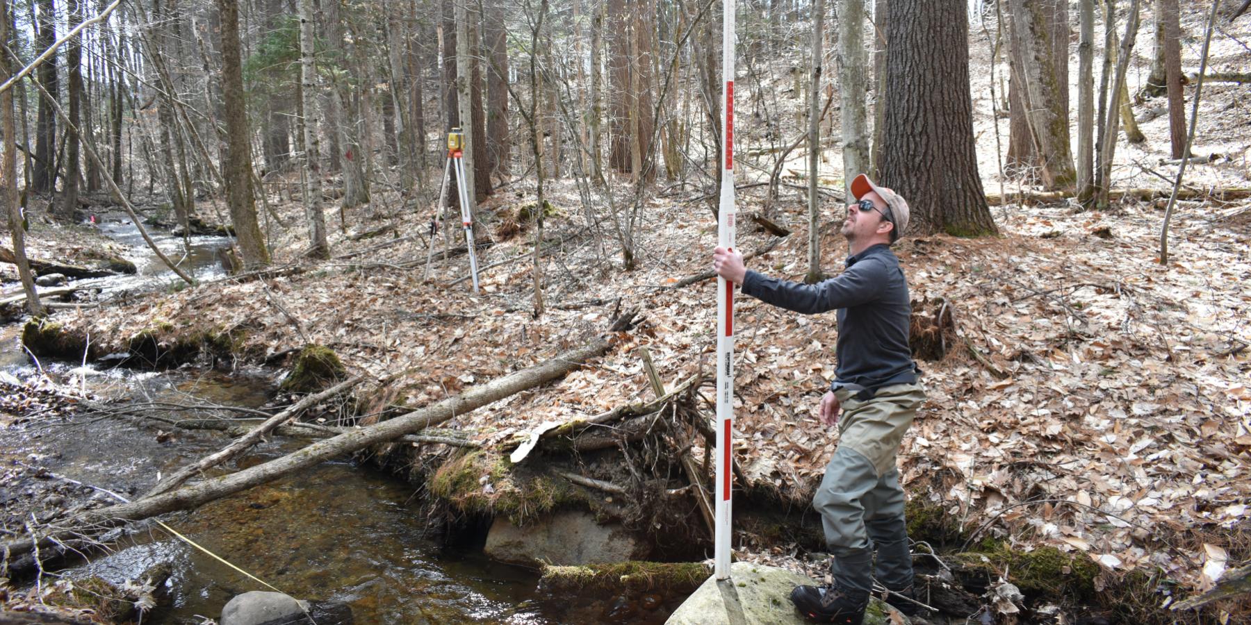A surveyor taking measurements in a small stream