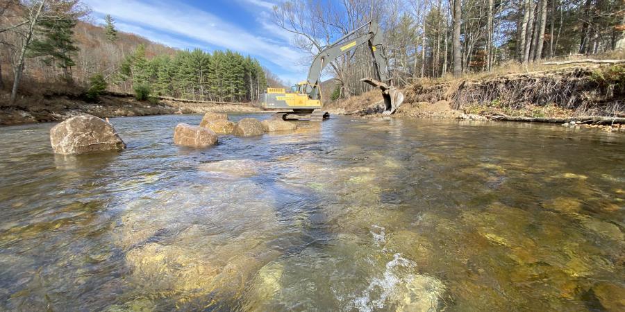 excavator in a natural river with blue sky above