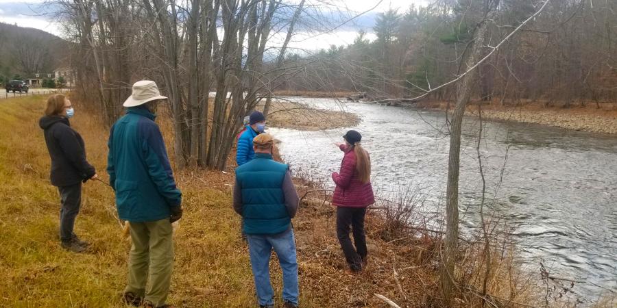 Executive director beside river explaining projects to group of members