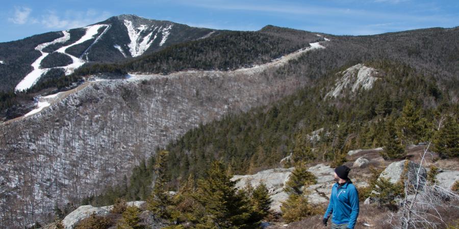 person on a ridge line looking back at a snowy ski resort