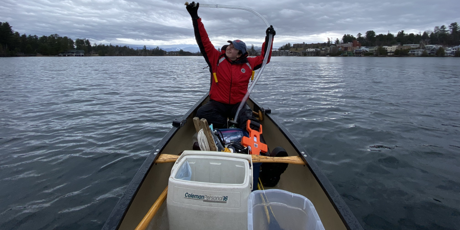 Woman in red using a sampler to take a surface sample on a lake 