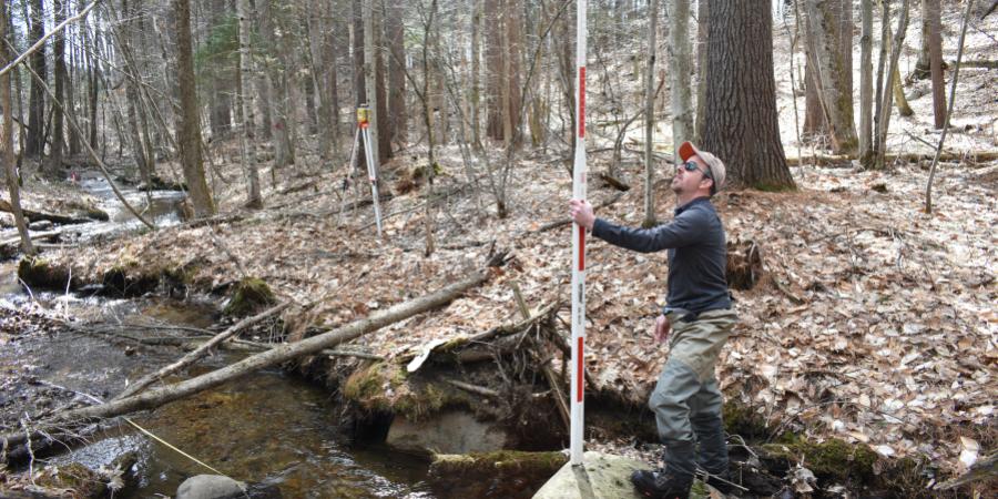A surveyor taking measurements in a small stream